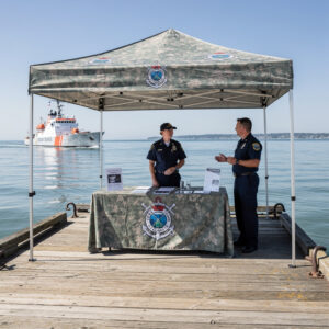 Coastguard camouflage popup tent on ocean pier with ship
